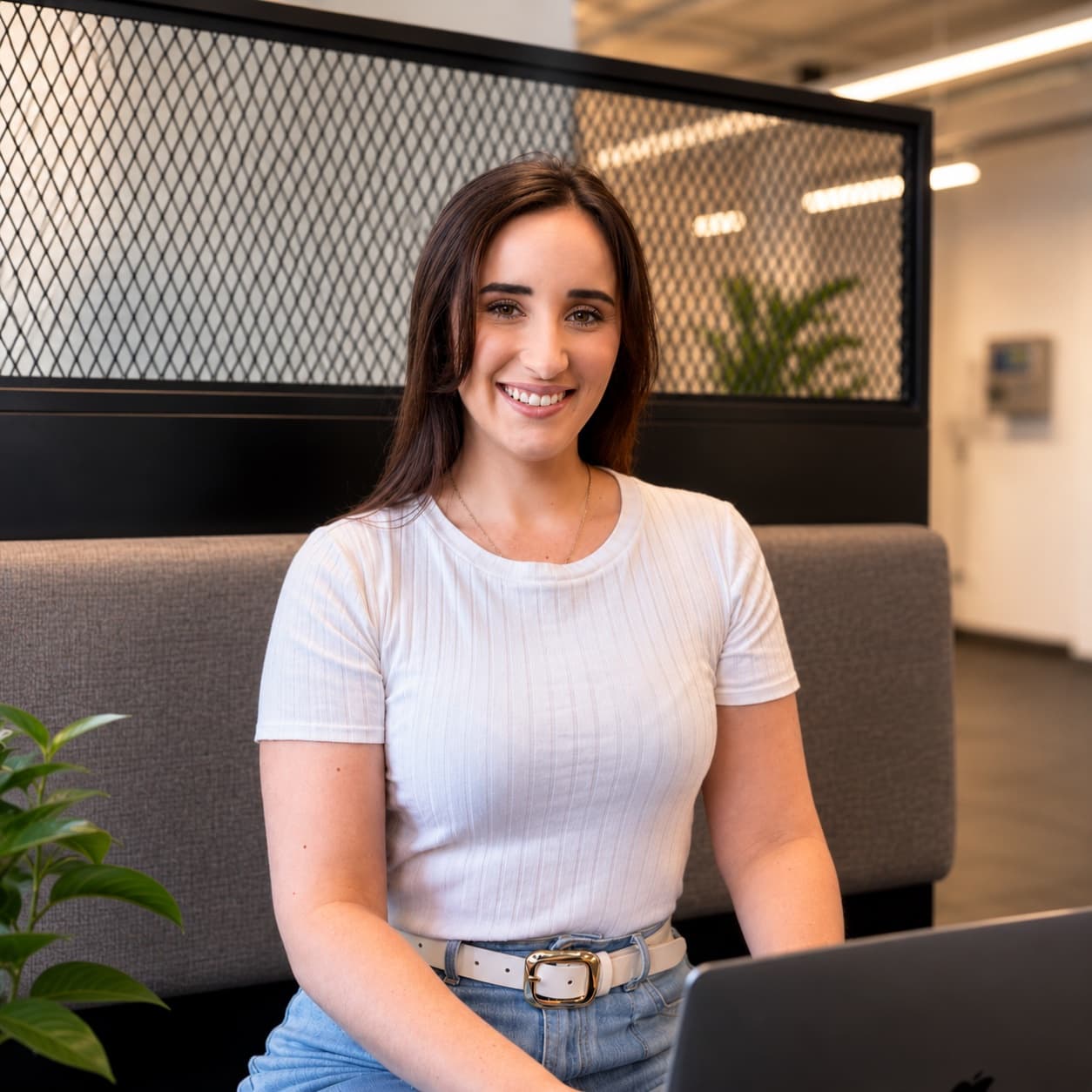 Alexia, founder of The Invisible Office, smiling at her laptop in a bright office